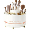 A white rotating makeup organizer holding various gold and bronze makeup brushes and tools.