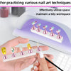 A hand is using a nail practice stand set with double-sided tape to apply nail art techniques on a white surface.