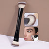 A black makeup brush with a fluffy synthetic hair is shown alongside close-ups of its use for foundation and concealer applic