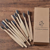 Une boîte en carton marron contenant dix brosses à dents en bambou sur une surface en bois.