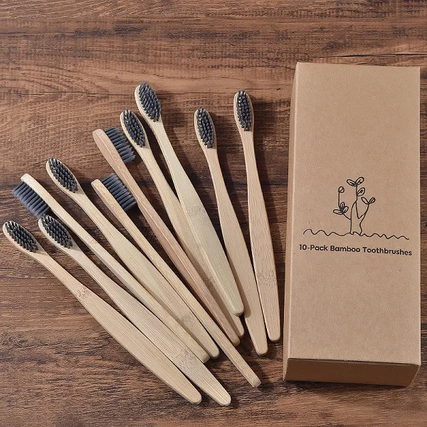 Une boîte en carton marron contenant dix brosses à dents en bambou sur une surface en bois.