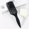 Peigne professionnel noir à cheveux bouclés avec dents blanches sur fond blanc.