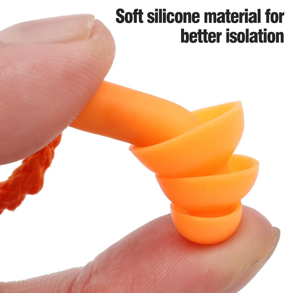 Une main serre un petit bouchon d'oreille en silicone orange vif pour réduire le bruit.