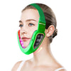 A woman is using a green facial lifting massager with LED photon therapy device on her face.