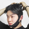 A person wearing a black reusable V-line lifting mask on their face, with hands adjusting their hair.