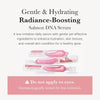 A bottle of Salmon DNA Serum with a pink liquid and white label is shown.