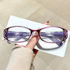 A pair of purple-tinted ultralight anti-blue light reading glasses resting on a white card.