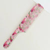 A pink and green dual hair comb with floral patterns, shown diagonally on a white background.
