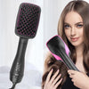 A woman is using a black and pink professional hot air brush hair styling tool on her hair.