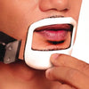 A hand holds a white shaving template against a person's upper lip and beard area.