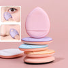 A set of pink and purple mini finger puff foundation applicator tools stacked on a surface.