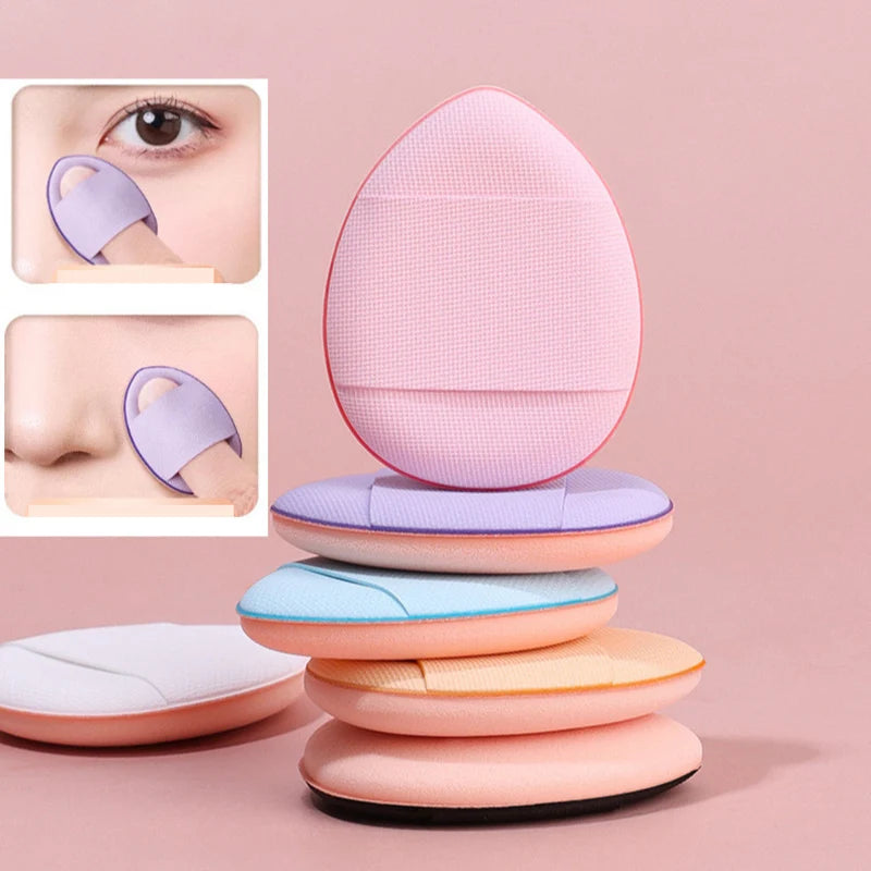A set of pink and purple mini finger puff foundation applicator tools stacked on a surface.