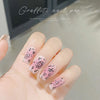 A hand displays detailed nail art featuring pink and white graffiti designs on the fingernails.