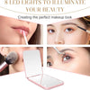 A pink mini folding makeup mirror with an LED light illuminating a woman's face for makeup application.