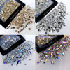 A collection of mixed glass rhinestones in various silver and gold tones displayed on a black background.