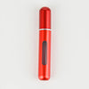 A red, cylindrical portable refillable perfume bottle with a silver band and a clear glass insert.