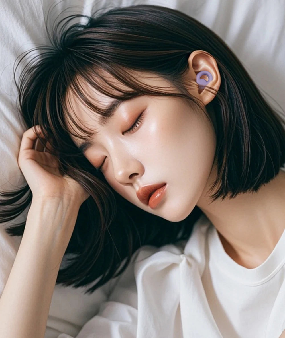 A close-up of a woman with dark hair lying down, gently touching her ear, wearing a purple silicone earplug.