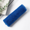 A blue reusable exfoliating bath sponge washcloth lying on a white surface next to a green plant.
