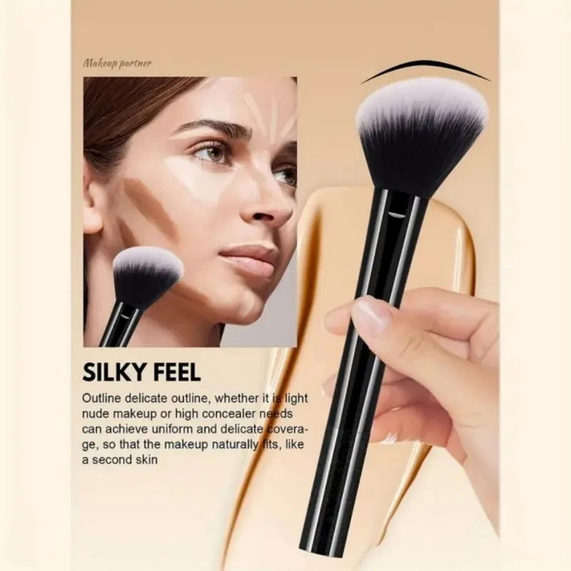 A close-up of a black makeup brush with a fluffy ferrule and a handle, shown next to a woman's face.