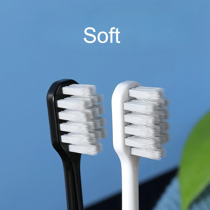 Une paire de brosses à dents à poils souples, une noire et une blanche, sont présentées sur un fond bleu.