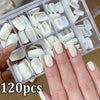 A hand holds a clear plastic box filled with 120 press-on nails in various shades of white and cream.