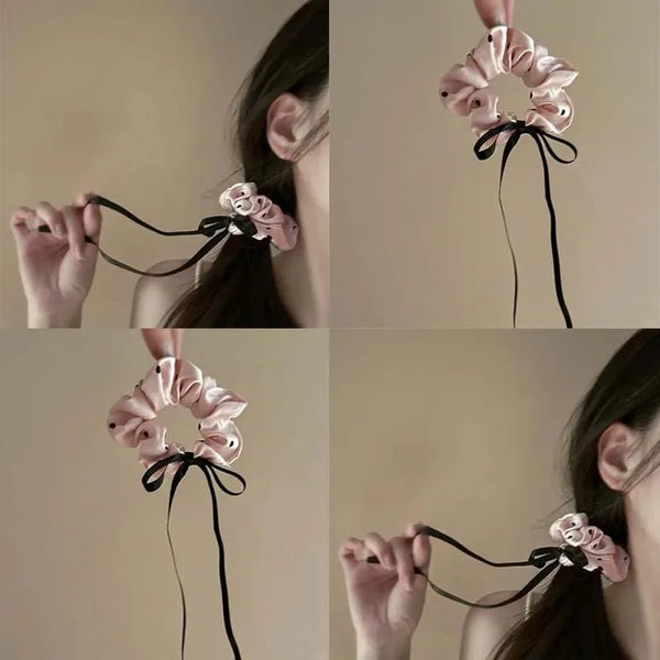 Pink polka dot satin hair scrunchies tied in a bow and displayed on a person's hair.
