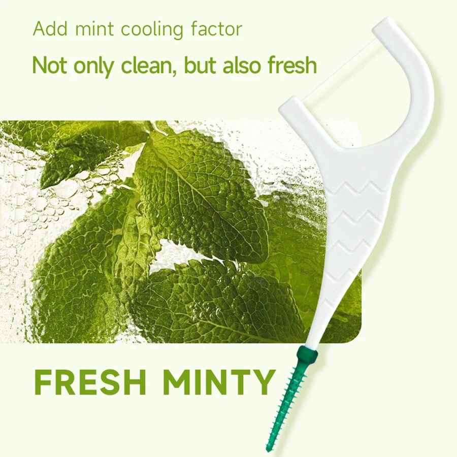 White silicone dental floss with an interdental brush and a green mint tip shown next to fresh mint leaves.