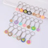 A set of 20 colorful cartoon smile face keychains hanging from metal rings on a white surface.