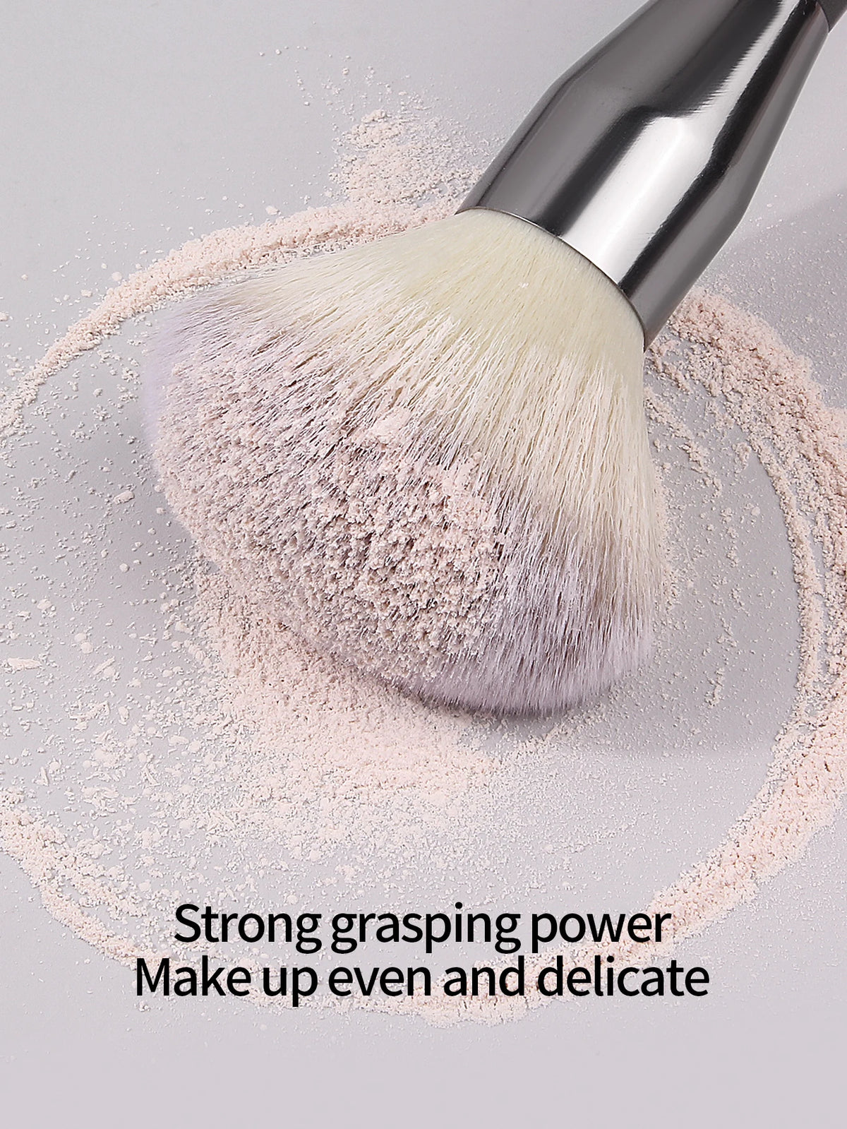 A silver face powder brush with soft pink powder is shown on a light gray surface.