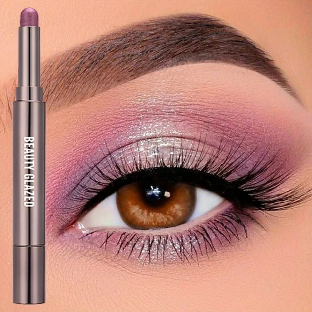 A cosmetic product showing a mauve eyeshadow stick with a brush on an eye.
