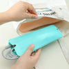A hand holds a light blue silicone mat with coiled wires, resting on a white cloth next to a hair styling tool.