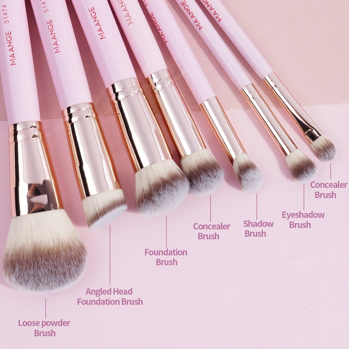 A collection of seven pink makeup brushes including concealer, foundation, eyeshadow, and loose powder brushes.