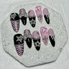 A set of glitter diamond press on nails featuring black, pink, and zebra print designs displayed on a white surface.