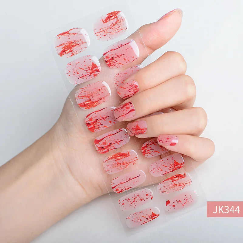A hand displays a set of red and pink Halloween UV gel nail stickers applied to fingernails.