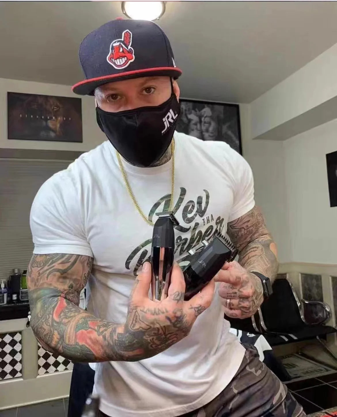 A man wearing a black mask and a baseball cap holds a professional rechargeable hair clipper.