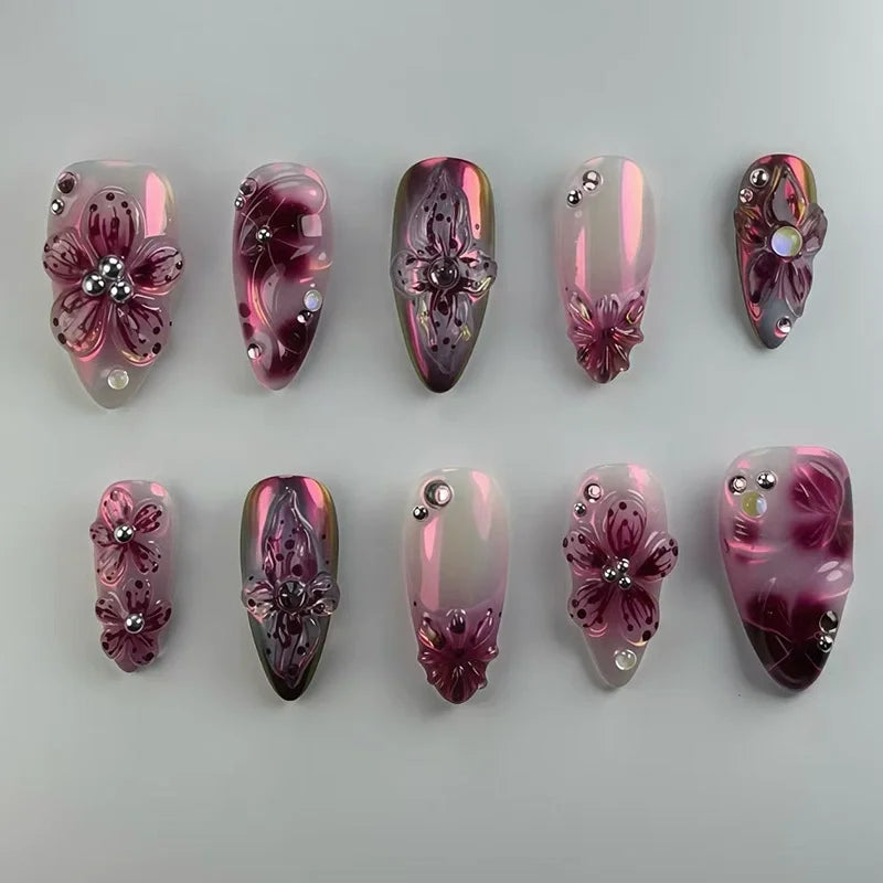 A collection of 24 press-on nails featuring a glossy pink and purple gradient with 3D floral and butterfly designs.