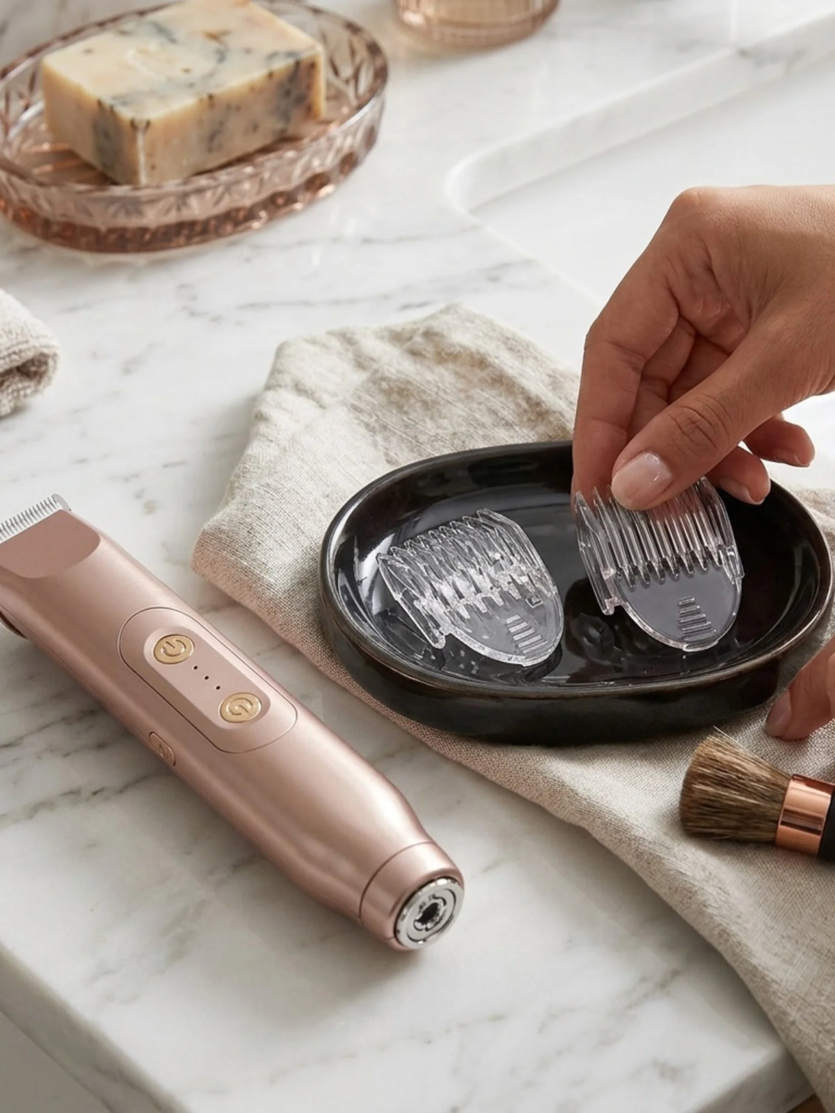 A hand holds a rose gold electric shaver epilator with a shaving head resting on a natural linen cloth.