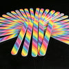 A fan of colorful dual-grit nail files arranged radially on a black surface.