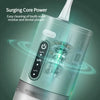 A close-up of a portable electric water flosser device with a green and silver body, showing the cleaning mechanism.