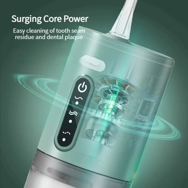 A close-up of a portable electric water flosser device with a green and silver body, showing the cleaning mechanism.