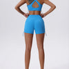 Una mujer modela un conjunto deportivo de yoga y gimnasio azul brillante, transpirable y de secado rápido, con top corto y sh