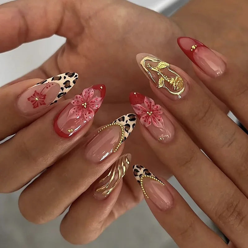Gros plan d'une main montrant un ensemble de faux ongles à almonds français roses avec des accents floraux.