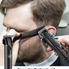A man is using a black rechargeable hair clipper to engrave patterns onto his beard.