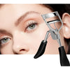 A close-up of a woman's eye being curled by a silver silicone eyelash curler tool.