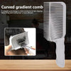 A white V-shaped curved gradient comb is shown next to a hair styling tool on a wooden surface.