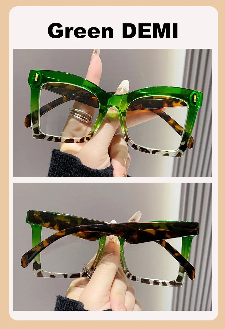 A pair of green patterned reading glasses shown on a hand.