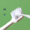 A white cartoon dinosaur toothbrush is shown being used on a green background.