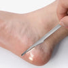 A hand is using a silver multi-piece foot care tool kit to remove dead skin from the sole of a foot.