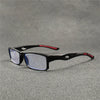 Gafas deportivas anti-luz azul negras con detalles rojos, apoyadas sobre una superficie gris.