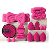 A collection of pink fuzzy makeup brushes and sponges displayed on a white surface.